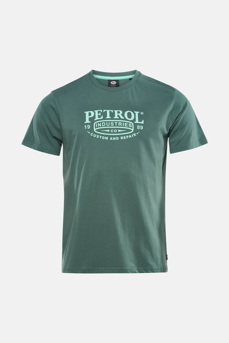 Groen T-shirt met korte mouwen van Petrol Industries®, gedragen met een donkergrijze jeans en beige lage sneakers.