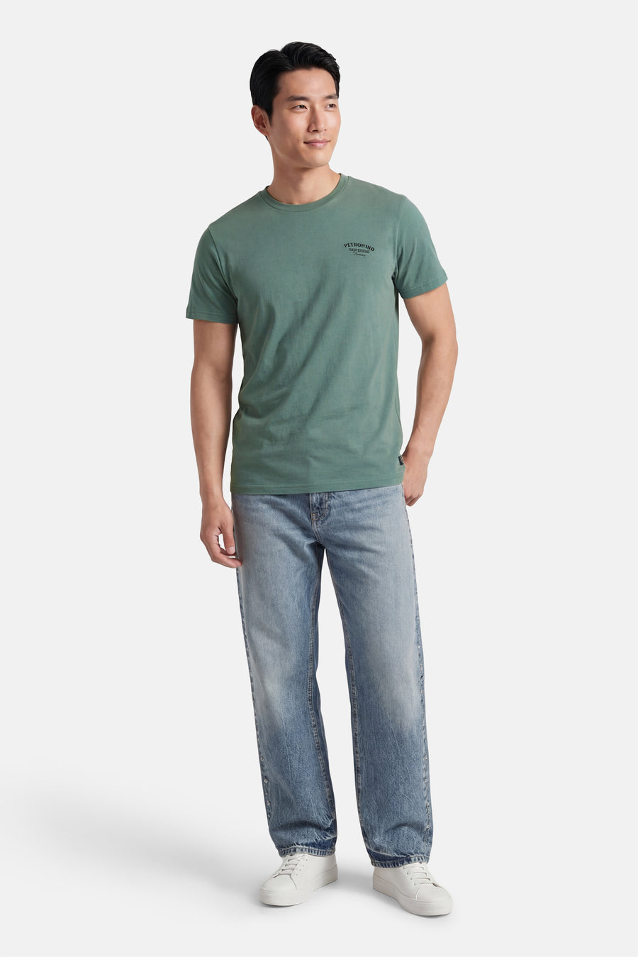 T-shirt à manches courtes vert de Petrol Industries, porté avec un jean bleu et des baskets blanches.