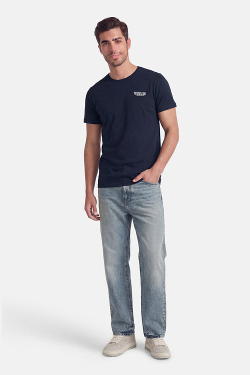 T-shirt à manches courtes bleu de Petrol Industries®, porté avec un jean délavé et des baskets blanches.