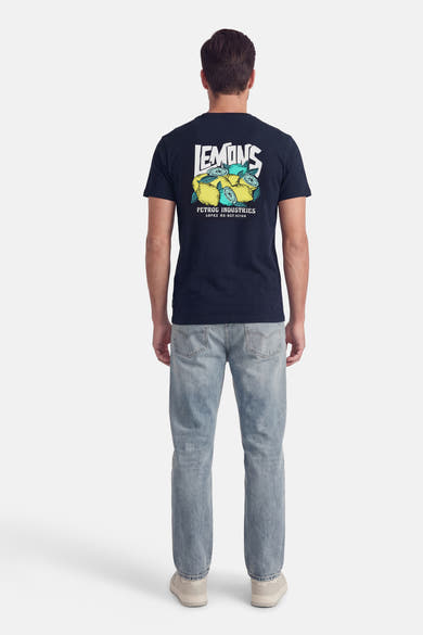 Blauw T-shirt met korte mouwen van Petrol Industries®, met citroenprint op de rug, gedragen met een versleten spijkerbroek en sneakers.