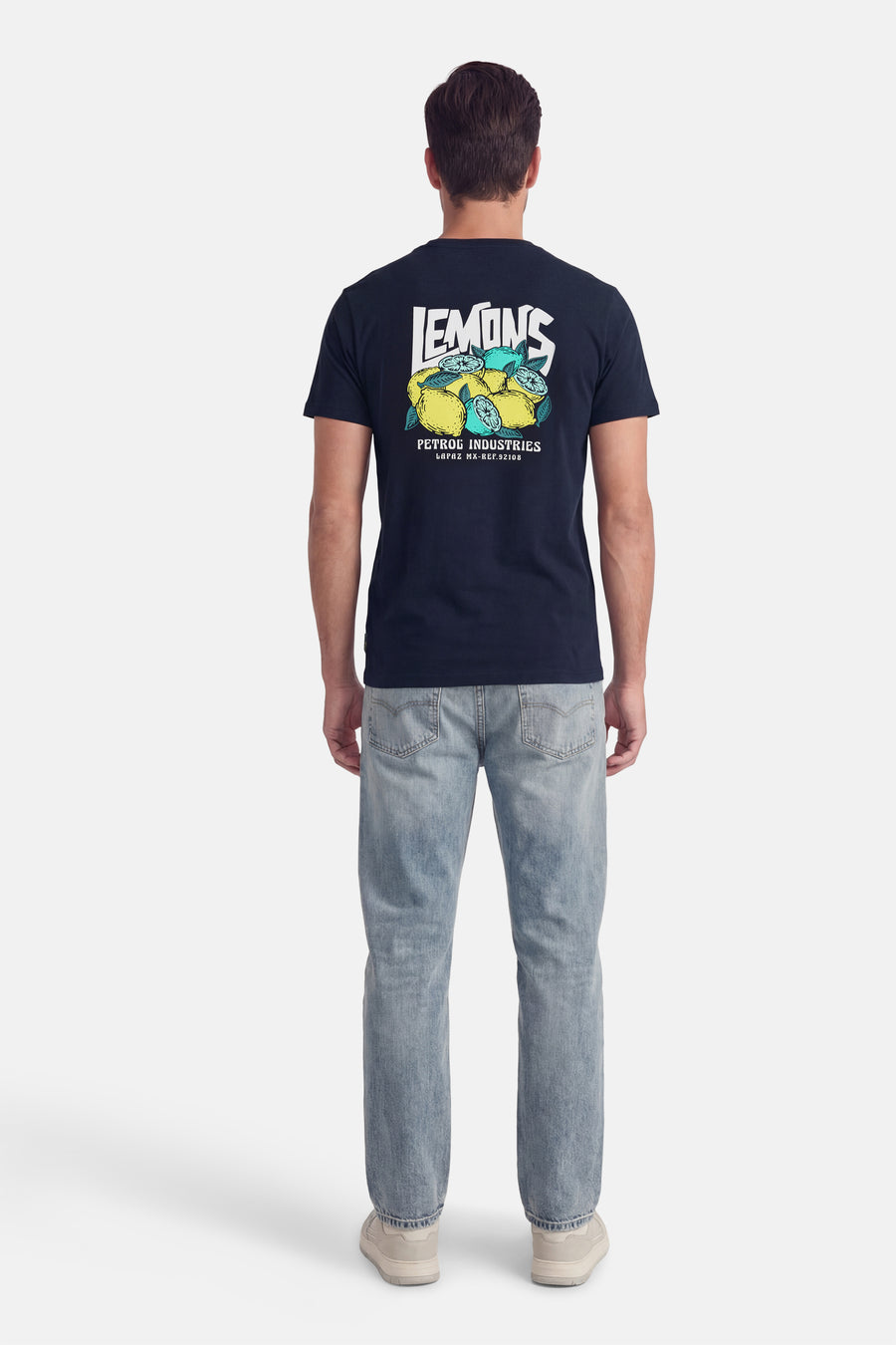 Blauw T-shirt met korte mouwen van Petrol Industries®, met citroenprint op de rug, gedragen met een versleten spijkerbroek en sneakers.