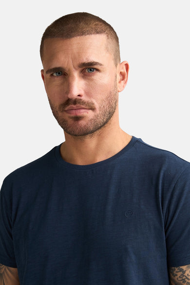 Blauw T-shirt met korte mouwen van Petrol Industries, gedragen door een man, op een effen achtergrond.