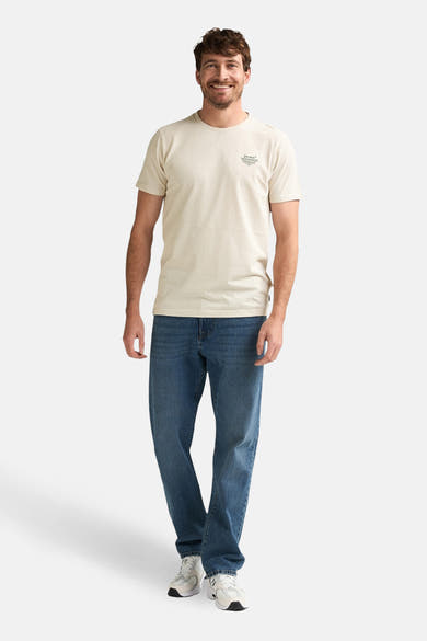 Beige T-shirt met korte mouwen van Petrol Industries, gedragen met een blauwe jeans en witte sneakers.