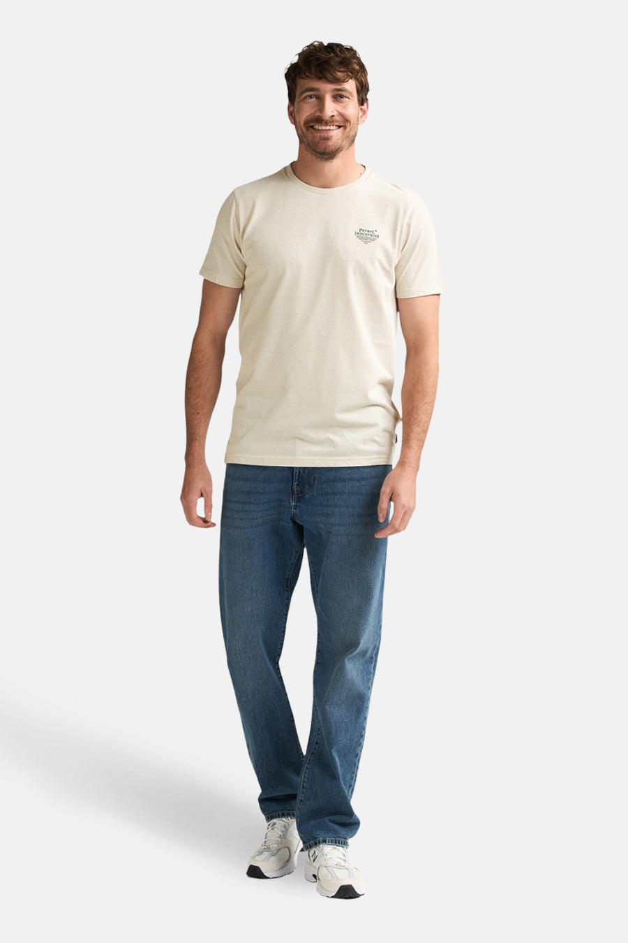 Beige T-shirt met korte mouwen van Petrol Industries, gedragen met een blauwe jeans en witte sneakers.