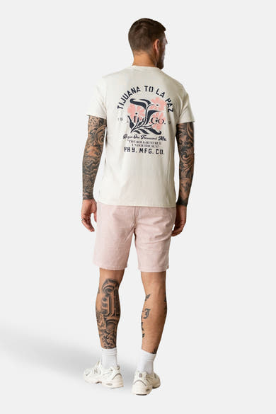 T-shirt à manches courtes écru de Petrol Industries®, avec imprimé dans le dos et porté avec un short rose.
