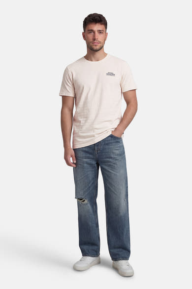 T-shirt à manches courtes beige de Petrol Industries avec un logo imprimé discret, porté avec un jean bleu destroy.