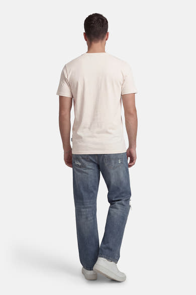 T-shirt à manches courtes beige de Petrol Industries®, vu de dos, porté avec un jean décontracté et des chaussures blanches.
