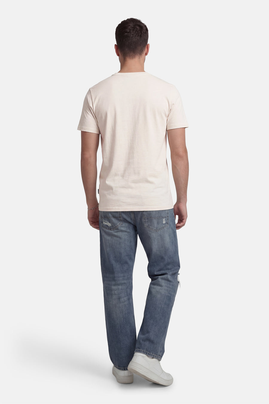 T-shirt à manches courtes beige de Petrol Industries®, vu de dos, porté avec un jean décontracté et des chaussures blanches.
