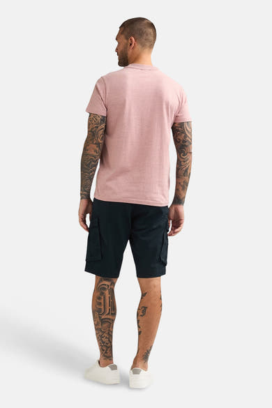 T-shirt corail de Petrol Industries®, porté avec un short cargo noir et des baskets blanches, vue de dos.

