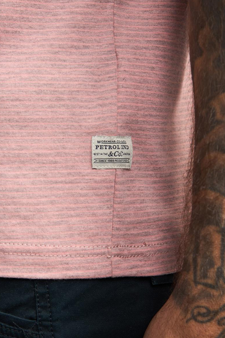 T-shirt corail à rayures horizontales par Petrol Industries, avec étiquette logo cousue et bas visible de pantalon bleu marine.