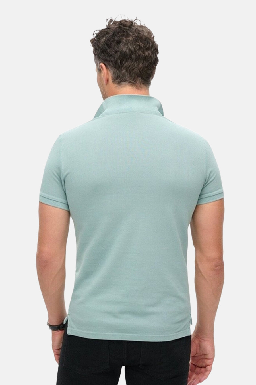 Polo bleu à manches courtes de Superdry, vue de dos, porté avec un pantalon noir et une montre.
