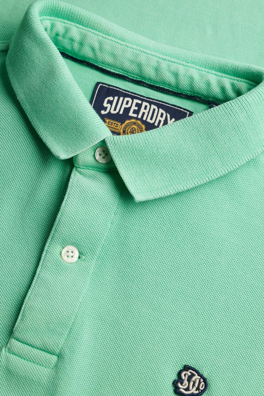 Mintgroen poloshirt van SUPERDRY, met witte knopen en discreet geborduurd logo.