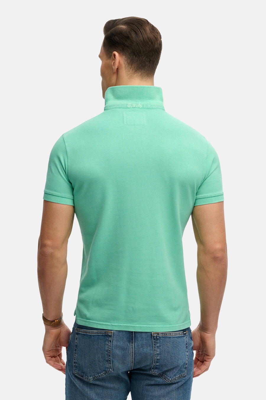 Polo vert par SUPERDRY, vue de dos, porté avec un jean bleu.