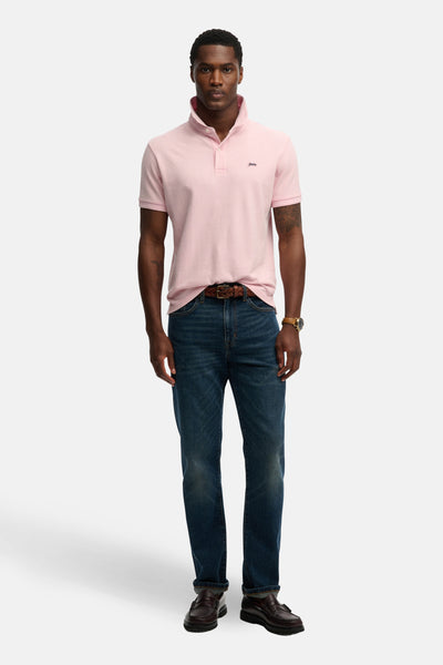 Roze poloshirt met korte mouwen van SUPERDRY, gedragen met een blauwe spijkerbroek en bruine schoenen.