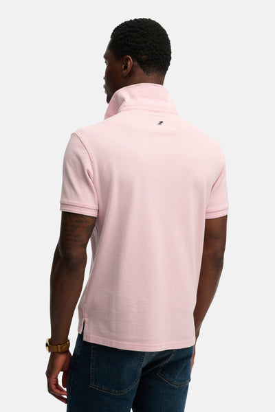 Roze poloshirt met korte mouwen van SUPERDRY, van achteren gezien, gedragen met een spijkerbroek en een armbandhorloge.