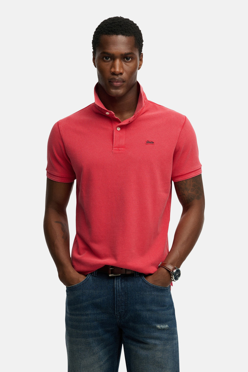 Roze poloshirt met korte mouwen van SUPERDRY, gedragen met een spijkerbroek en een horloge met leren band.
