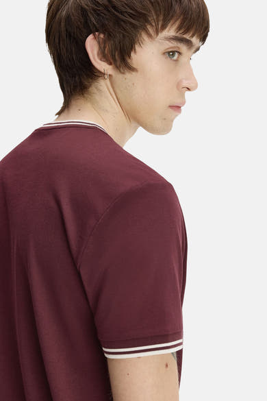Bordeaux short-sleeve t-shirt with white striped neckline and cuffs, side view on model