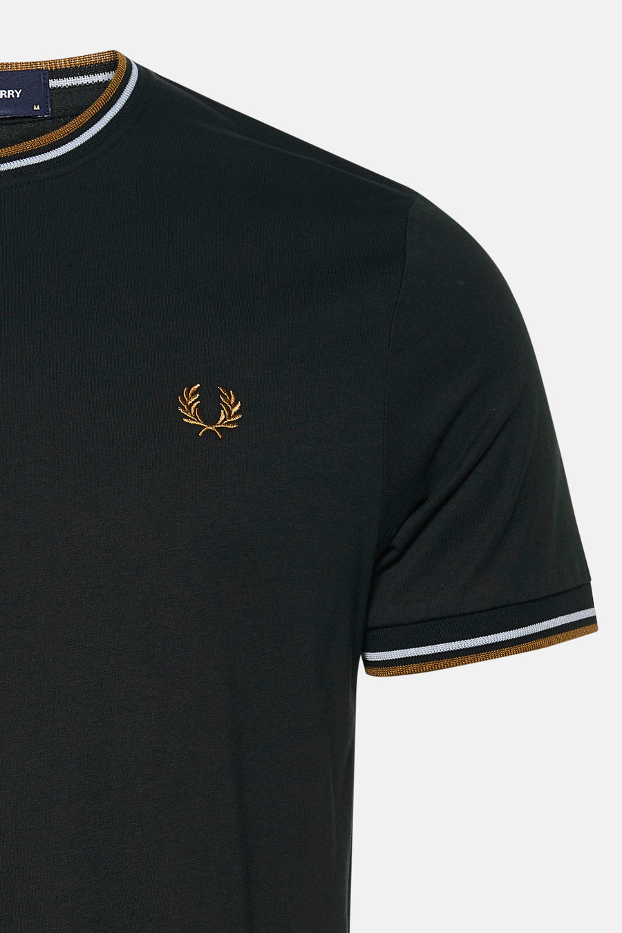 Détail d’un T-shirt FRED PERRY à manches courtes noir, avec col et bord de manche rayés et logo brodé doré.
