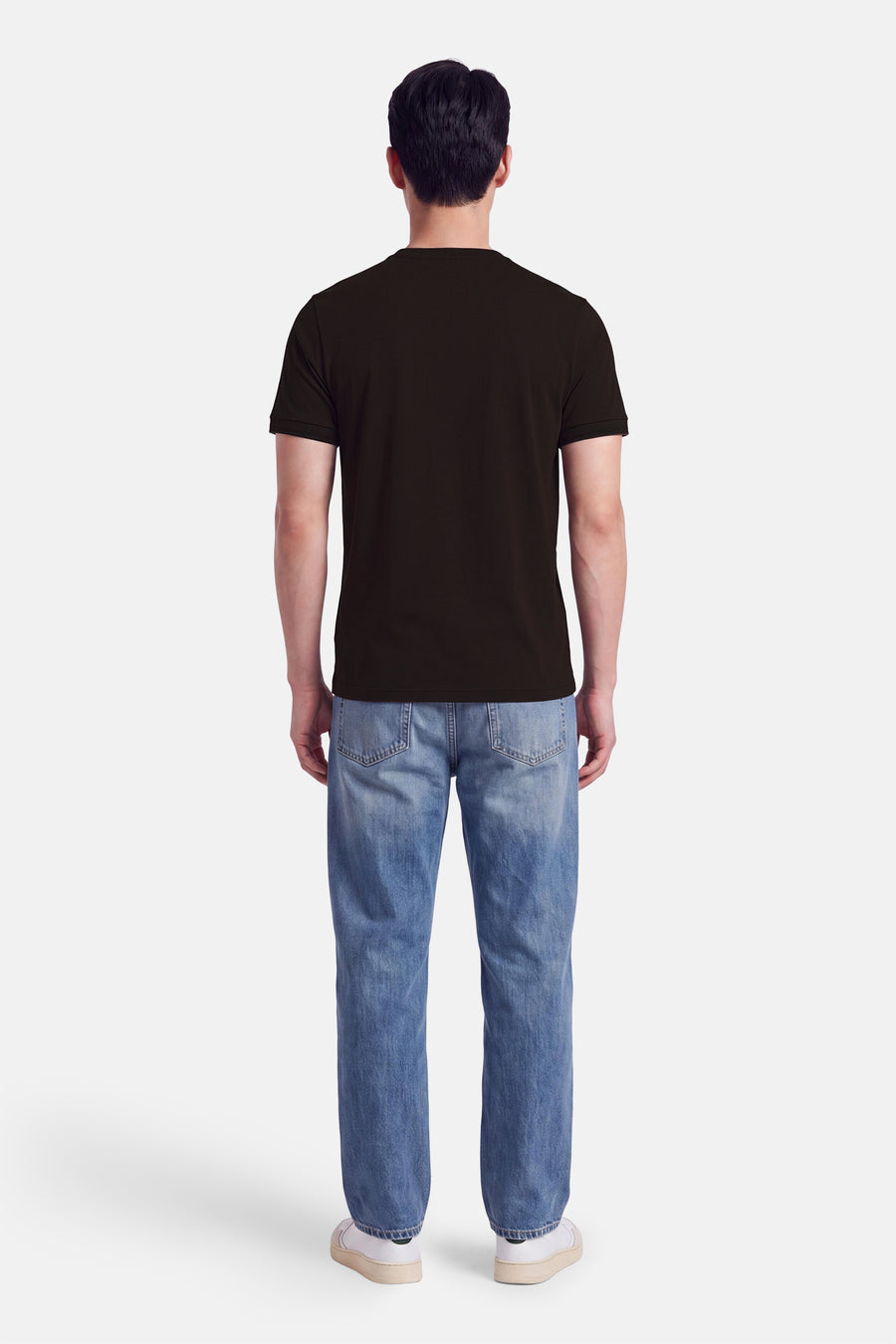 Vue de dos d’un homme portant un T-shirt à manches courtes brun FRED PERRY et un jean bleu.