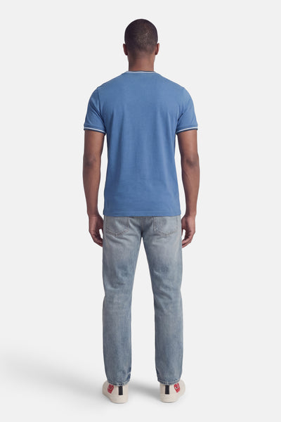 Blauw T-shirt met korte mouwen van FRED PERRY, met contrasterende afwerkingen aan de kraag en mouwen, gedragen met een verbleekte spijkerbroek en sneakers.