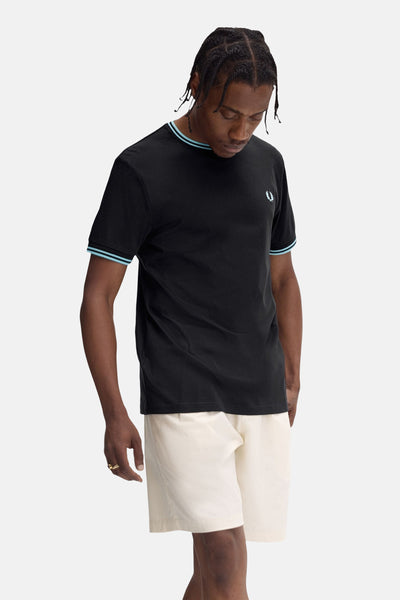 T-shirt noir à manches courtes de Fred Perry avec détails rayés bleus au col et aux manches.