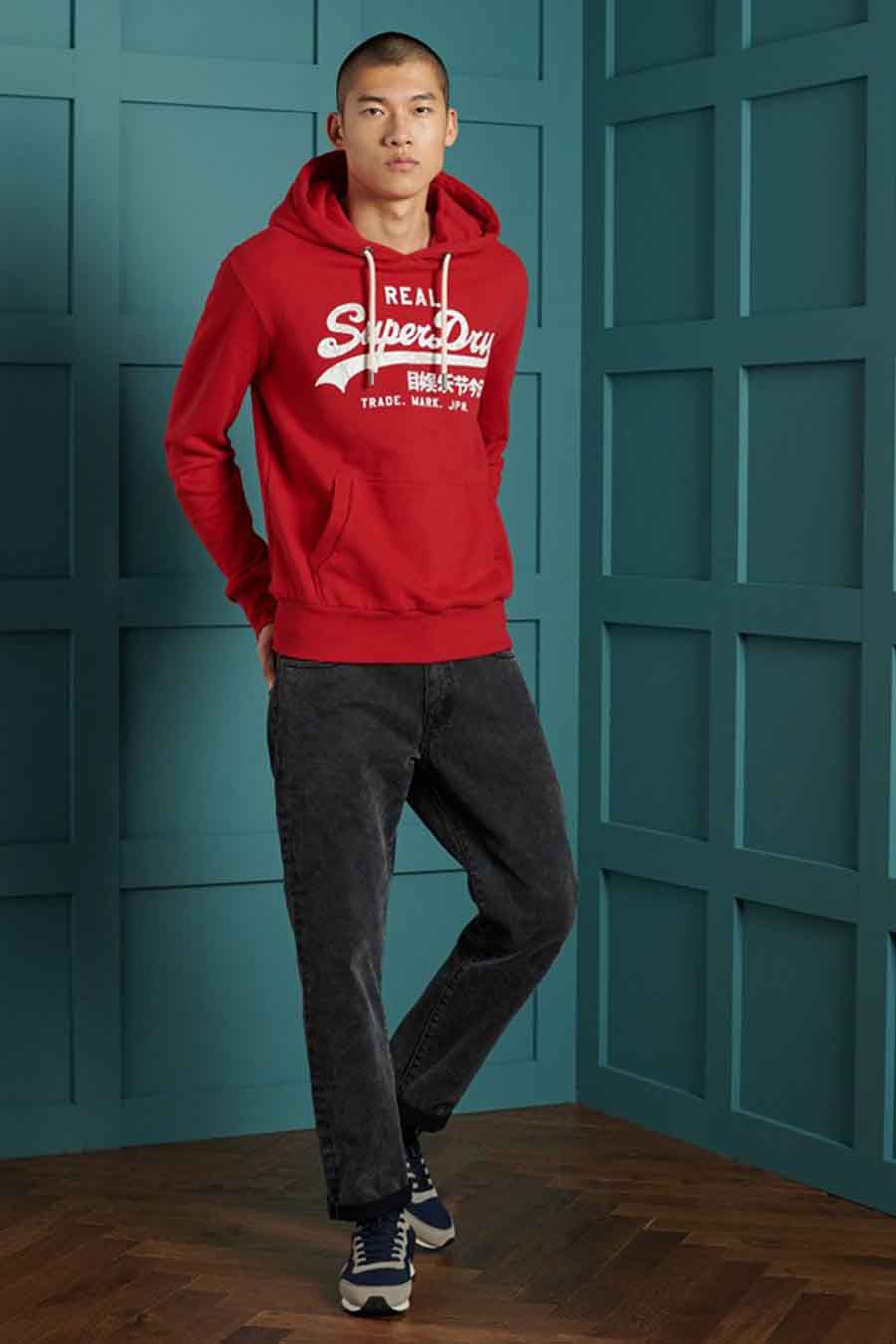 Rode SUPERDRY hoodie, gedragen met een zwarte jeans en sneakers.