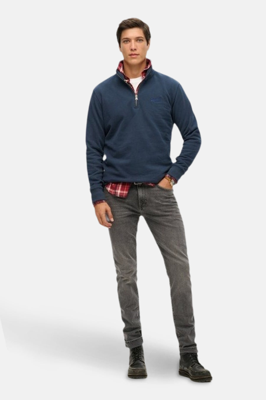 Marineblauwe sweatshirt met ritssluiting van SUPERDRY, gedragen over een rood geruit overhemd en grijze jeans.