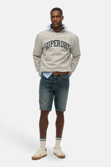 Sweat-shirt gris à col rond de SUPERDRY, porté avec une chemise, un short en jean et des baskets.
