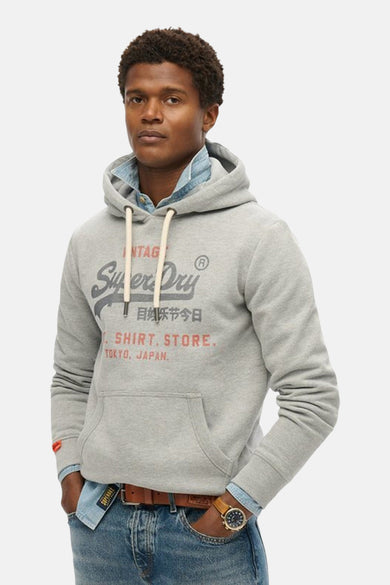 Grijze gestreepte hoodie van SUPERDRY, gezien van achteren, gedragen met een jeanshemd en een denimbroek.