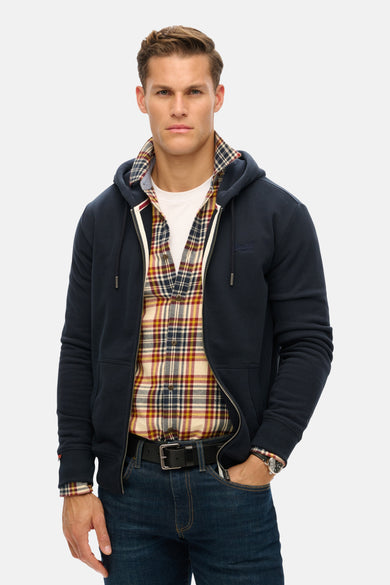 Donkerblauwe bodywarmer van SUPERDRY met ritssluiting, gedragen over een geruit overhemd.