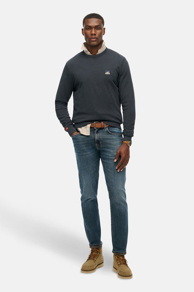 Blauwe trui van SUPERDRY, gedragen over een beige overhemd met een spijkerbroek en bruine laarzen