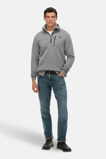 Grijs gemêleerde fleece van SUPERDRY, gedragen over een geruit overhemd, met een spijkerbroek en leren schoenen.