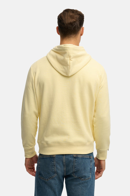 Sweat à capuche jaune de Superdry, modèle uni vu de dos, porté avec un jean bleu.