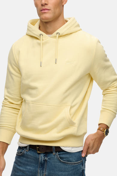 Sweat à capuche jaune par SUPERDRY, avec cordon de serrage, poche kangourou et porté avec un jean et une ceinture marron.
