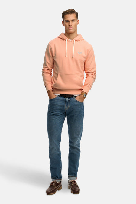 Sweat à capuche orange de SUPERDRY, porté avec un jean bleu, une ceinture marron et des chaussures bateau.