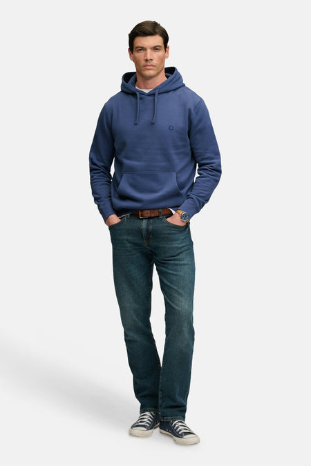 Sweat à capuche bleu de SUPERDRY, coupe classique, poche kangourou, cordon de serrage, porté avec jeans et baskets.