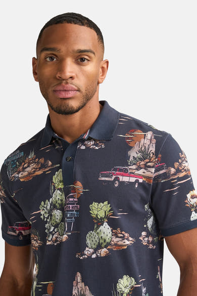 Marineblauwe meerkleurige polo van Petrol Industries met woestijnmotieven met cactussen en retroauto's.