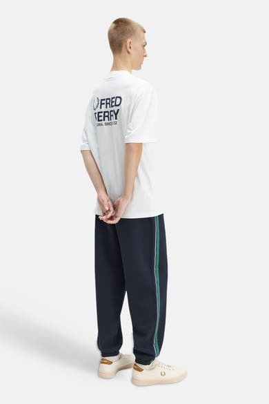 T-shirt blanc de Fred Perry avec un grand logo marine au dos, porté par un homme de dos.