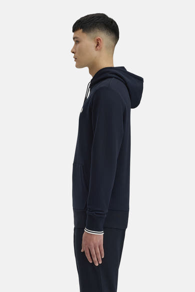 Sweat à capuche bleu foncé de Fred Perry, avec cordon de serrage et bordures à rayures blanches sur les poignets.