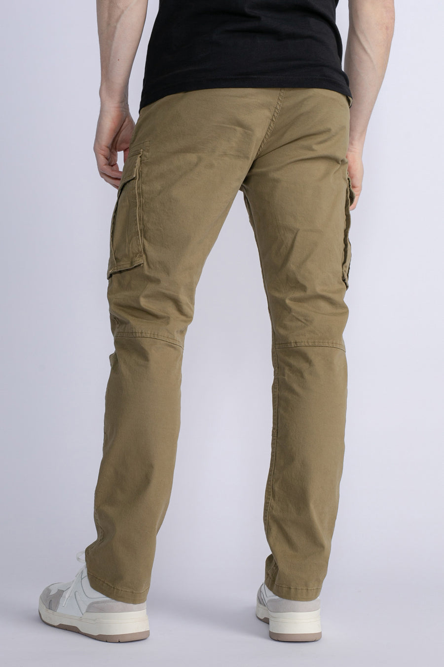 Groene cargobroek van Petrol Industries®, met cargozakken en gedragen met een zwart T-shirt en witte sneakers.