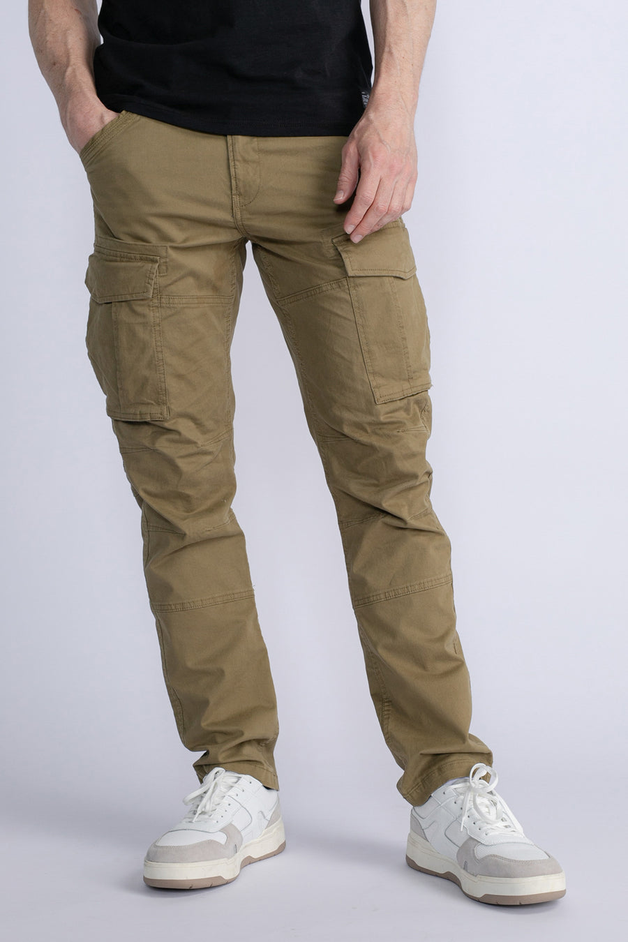 Groene cargobroek van Petrol Industries, met zijzakken en een nauwsluitende pasvorm, gedragen met witte sneakers.