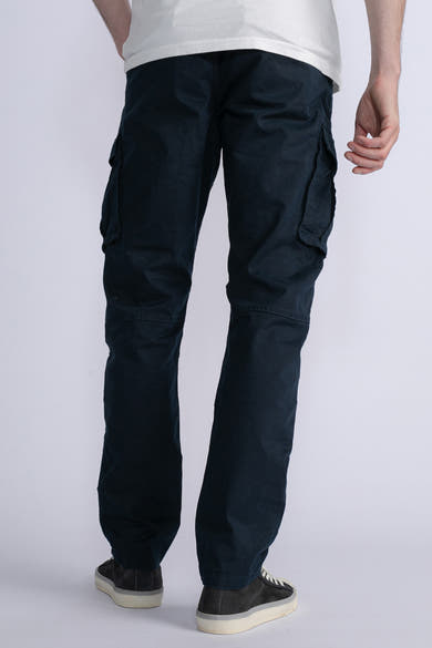 Marineblauwe cargobroek van Petrol Industries, met zijzakken, gedragen met een wit T-shirt en sneakers.