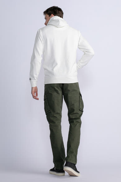 Groene cargobroek van Petrol Industries, gedragen met een witte hoodie en zwarte schoenen.