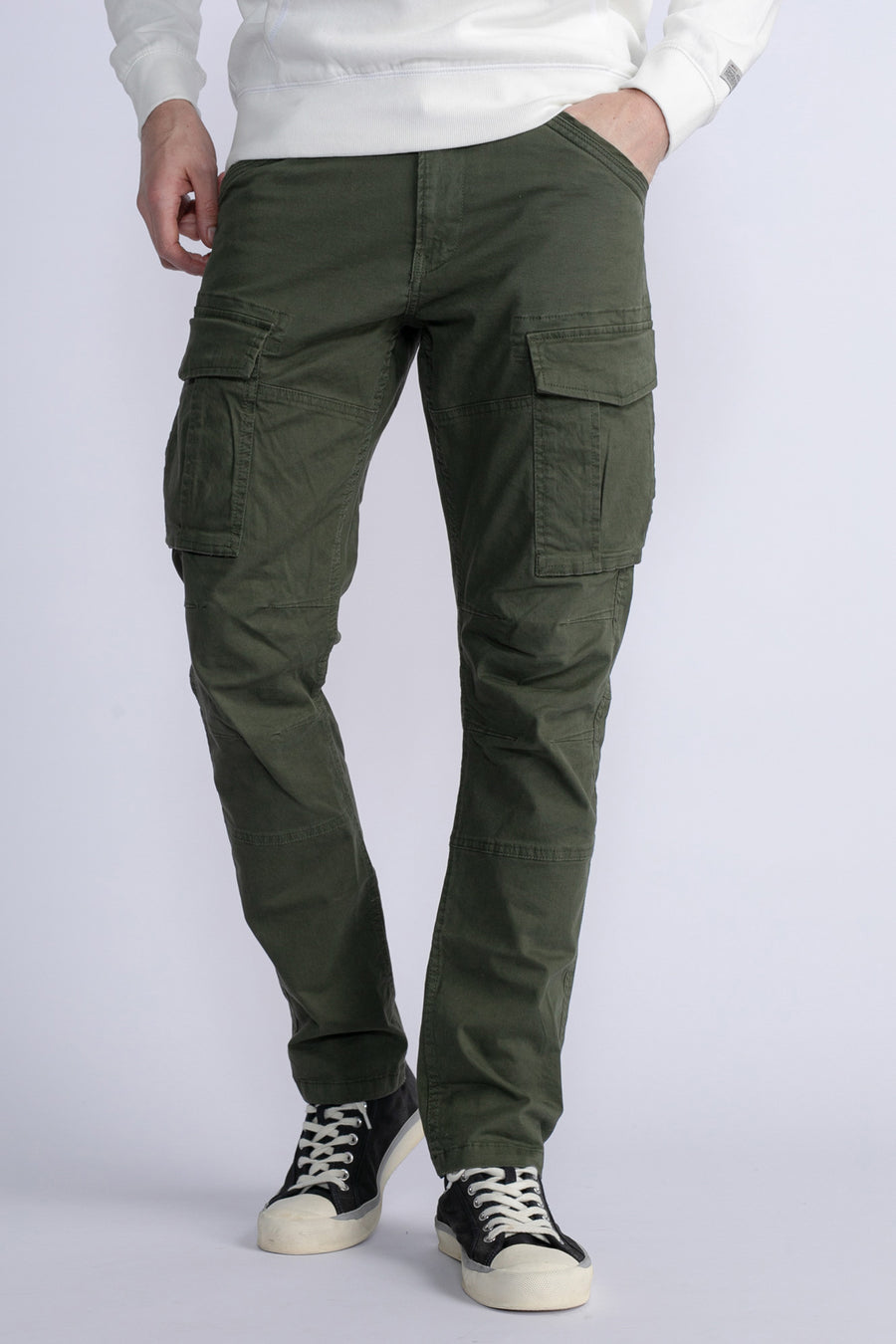 Groene cargobroek van Petrol Industries®, met cargozakken en gedragen met een witte trui en zwarte sneakers.