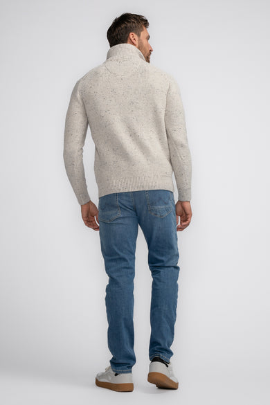 Pull à col roulé écru de Petrol Industries, en maille texturée, porté avec un jean bleu.
