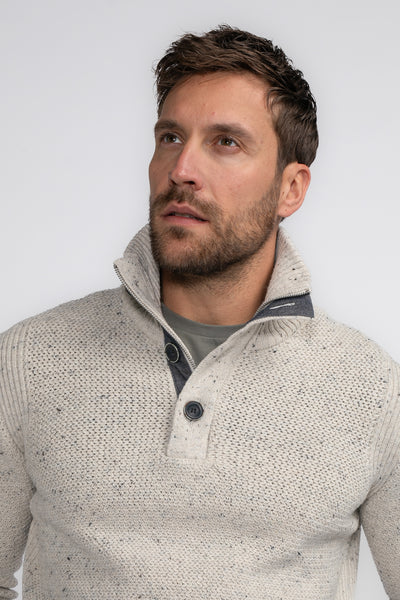 Pull à col roulé écru de Petrol Industries, avec fermeture boutonnée, en tricot texturé, porté sur un t-shirt uni.