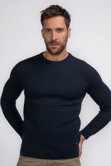Pull bleu à col rond de Petrol Industries, avec texture tricotée, porté avec un pantalon kaki.