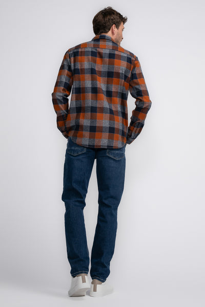 Chemise à manches longues cognac par Petrol Industries®, à carreaux orange, gris et bleu marine, portée avec un jean et des baskets blanches.