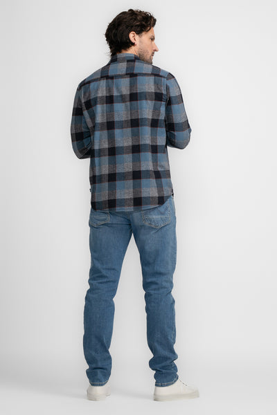 Chemise à manches longues bleue à carreaux par Petrol Industries® portée avec un jean bleu et des chaussures blanches.