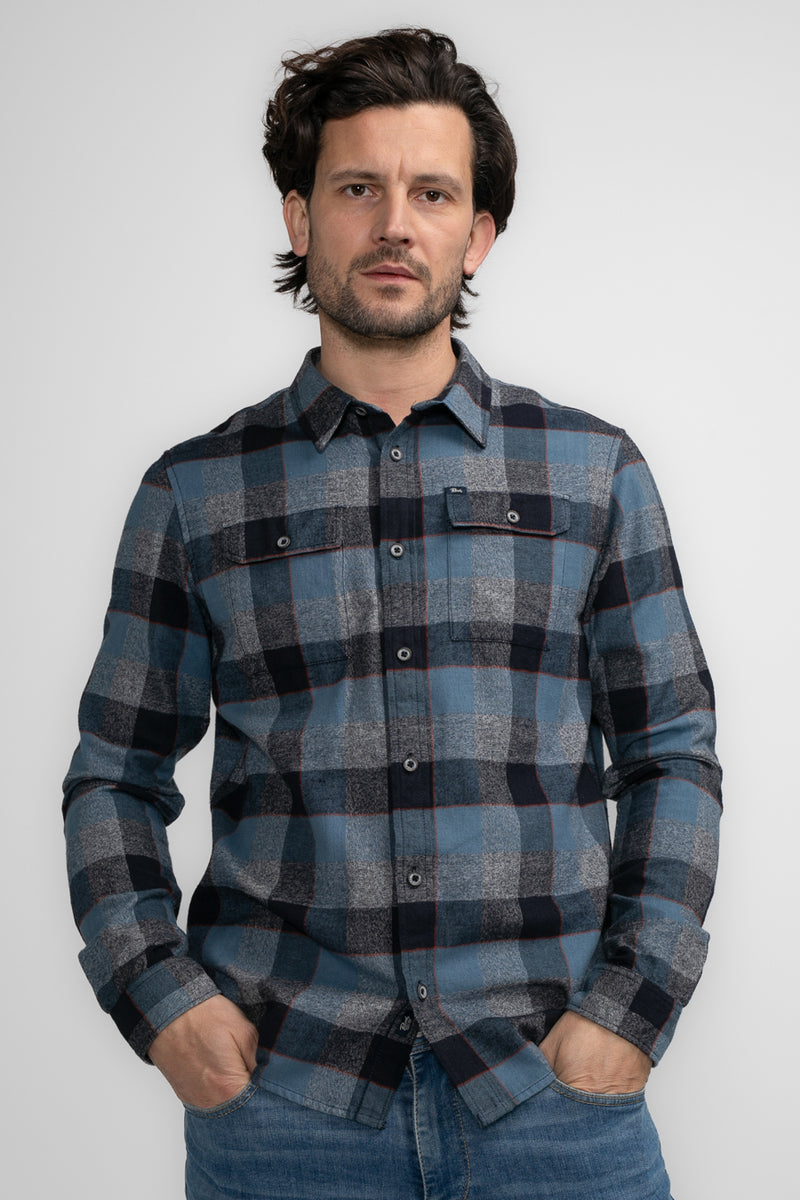 Chemise à manches longues bleue à carreaux par Petrol Industries, portée avec un jean décontracté.
